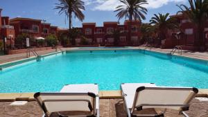 una gran piscina con 2 sillas frente a un edificio en Romantic Sunny Apartment, en Corralejo