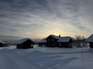 a house in the snow with the sun in the sky at Cozy Cabin With Ski Trail Access in Beitostøl
