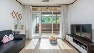 a living room with a black couch and a flat screen tv at Gapyeong Areuno Pet Pension in Gapyeong