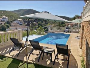 a patio with chairs and an umbrella next to a pool at Chambre avec piscine, jacuzzi, vue mer et montagne, plage à pied in Roquebrune-sur-Argens