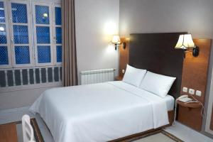 a bedroom with a large white bed and a phone at Hotel karim Tunis in Tunis