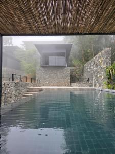 a swimming pool with a wooden roof and a house at Elevate Ella Resort & Spa in Ella