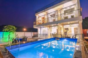 a villa with a swimming pool at night at ll EMPYREAN STAY ll LUXE ll FORTUNE VILLA ll 4BHK ll AC ll BIG POOL in Lonavala