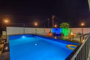 a swimming pool at night with blue lights on it at ll EMPYREAN STAY ll LUXE ll FORTUNE VILLA ll 4BHK ll AC ll BIG POOL in Lonavala +13 photos
