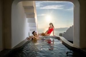 a man and a woman sitting in a swimming pool at Pegasus Suites & Spa in Imerovigli +123 photos