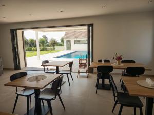 a restaurant with tables and chairs and a swimming pool at Les Hôtes des Maillets in Les Maillys