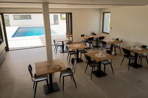 a restaurant with tables and chairs and a swimming pool at Les Hôtes des Maillets in Les Maillys