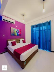 a bedroom with a large bed with purple walls at Lakshani Villa in Polonnaruwa