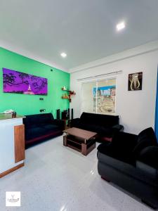 a living room with black couches and a green wall at Lakshani Villa in Polonnaruwa +56 photos