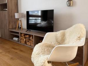 a living room with a white chair and a tv at Schliersee-Lounge in Schliersee