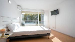 a white bedroom with a bed and a window at Le St Clair N208 ST2 in Agde