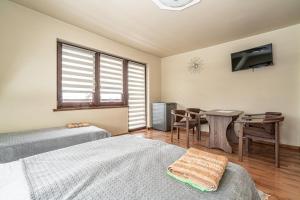 a bedroom with two beds and a table and a window at Dom Na Borku Józefa Schulz in Ciche