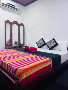 a bed with a colorful blanket on top of it at Villa Beach Heaven in Hikkaduwa