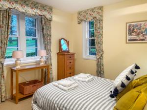 a bedroom with a bed and two windows at Baldowrie Lodge in Ardler