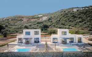 a large white house with a hill in the background at Ventalia Villas, 3BR Sea View and Infinity Pool by Villa Mana Gers in Agios Nikolaos