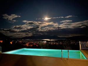 a swimming pool at night with a full moon at Villa Christina Nidri in Nydri