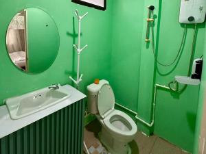 a green bathroom with a toilet and a sink at OYO 75539 Phanthida Resort and Cafe in Hua Hin