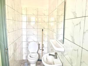 a white bathroom with a toilet and a sink at HEBERTOGO Casablanca in Lomé +54 photos