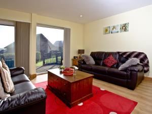 a living room with leather couches and a coffee table at Beech Lodge - Retallack Resort in Saint Columb Major