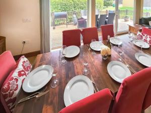 a wooden table with plates and wine glasses on it at Beech Lodge - Retallack Resort in Saint Columb Major