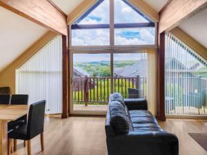 a living room with a couch and a large window at Beech Lodge - Retallack Resort in Saint Columb Major +19 photos