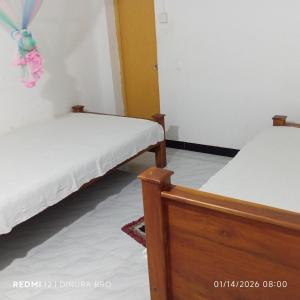 two beds in a room with white walls at Cattleya Guest House in Tissamaharama