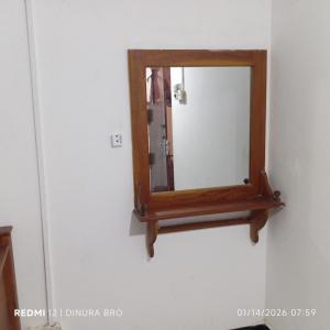 a mirror with a wooden frame hanging on a wall at Cattleya Guest House in Tissamaharama