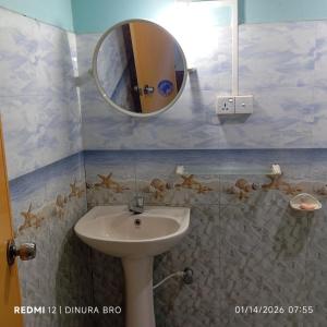 a bathroom with a sink and a mirror at Cattleya Guest House in Tissamaharama