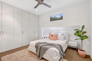 a white bedroom with a bed and a ceiling fan at Spring Hill Holiday Units - Queenscliff in Queenscliff