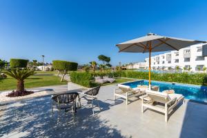 a patio with chairs and an umbrella next to a pool at Sunrise Crystal Bay Resort -Grand Select in Hurghada