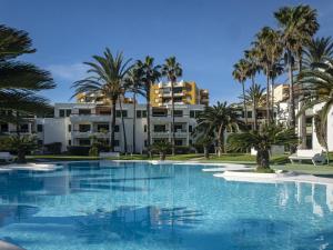 a swimming pool with palm trees and buildings at Deltamar Solo Familias Serviplaya in Xeraco