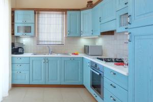 a kitchen with blue cabinets and a sink at Sea Views at villa Anemomylos with Heated Pool, Ping Pong and Tennis in Agia Pelagia
