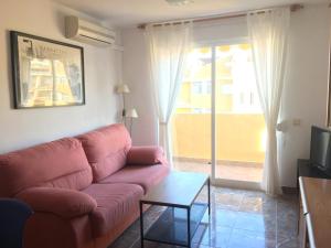 a living room with a pink couch and a sliding glass door at Xaloc Solo Familias Serviplaya in Playa de Xeraco