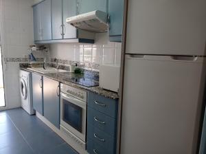 a kitchen with blue cabinets and a white refrigerator at Palmeras III Solo Familias Serviplaya!!! in Gandía