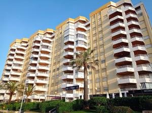 a large apartment building with palm trees in front of it at Bahamas II Solo Familias Serviplaya in Playa de Gandia