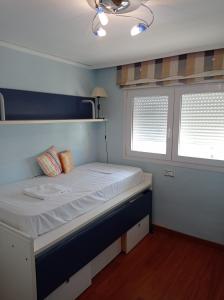 a bed in a room with two windows at Bahamas II Solo Familias Serviplaya in Playa de Gandia +37 photos