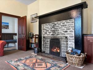 a living room with a stone fireplace with a basket at High Rylands in Arncliffe