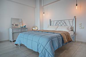 a bedroom with a bed with a blue blanket and a mirror at Sea Views at villa Anemomylos with Heated Pool, Ping Pong and Tennis in Agia Pelagia