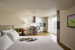 a bedroom with a white bed and a kitchen at Base Geneva in Geneva