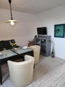 a living room with a table and chairs and a television at Watt in Karolinenkoog