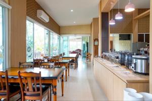 a restaurant with wooden tables and chairs and a kitchen at Tho Mai Resort in Wang Chan