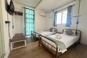 two beds in a room with a tv and a tv at Memmoth Cafe & Hostel in Lampang in Lampang