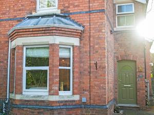 a brick building with a green door and a window at The Front House in Great Malvern