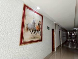 a painting of horses on a wall in a hallway at Veerakit Grand Hotel Udon Thani in Udon Thani