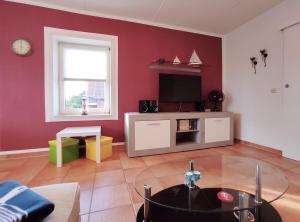 a living room with a red wall with a tv at Ostseeliebe in Kirchdorf