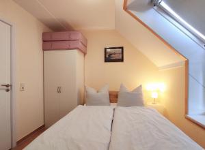 a bedroom with a bed with white sheets and pillows at Ostseeliebe in Kirchdorf