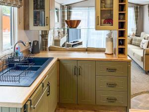 a kitchen with green cabinets and a sink at Lodge 58 in Aviemore