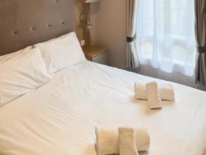 a white bed with two towels on top of it at Lodge 58 in Aviemore