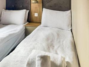 two beds in a small room with white sheets at Lodge 58 in Aviemore