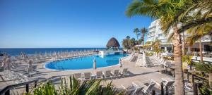 a swimming pool with chaise lounge chairs and the ocean at Princess Taurito in Taurito